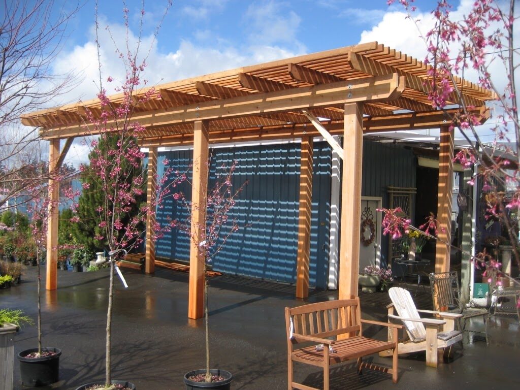 a wooden pergola with chairs and trees