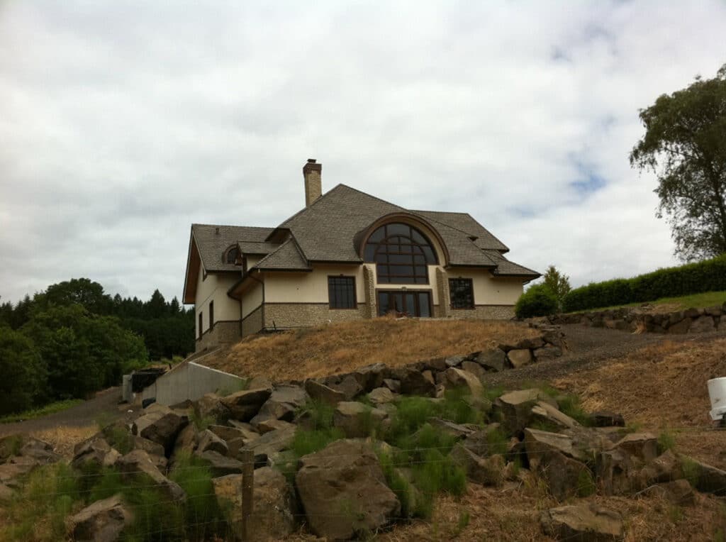 Exterior view of hillside home featuring newly installed custom arched window