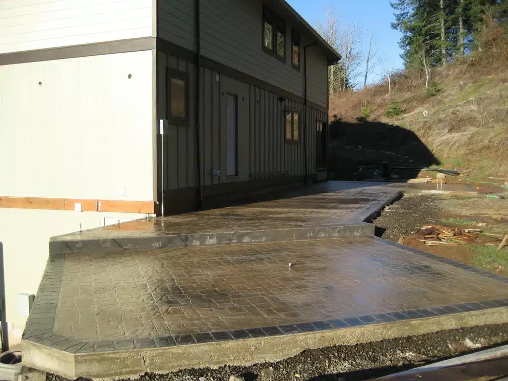 Stamped concrete patio leading around side of home
