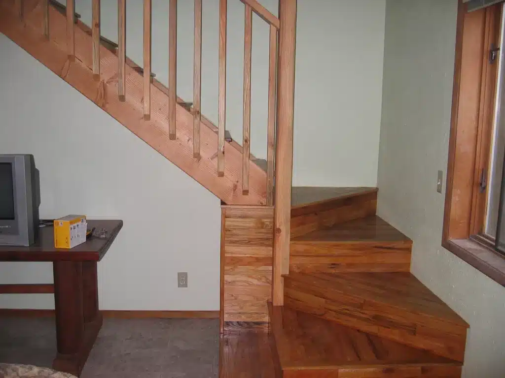 Hardwood staircase and railing beside living area window