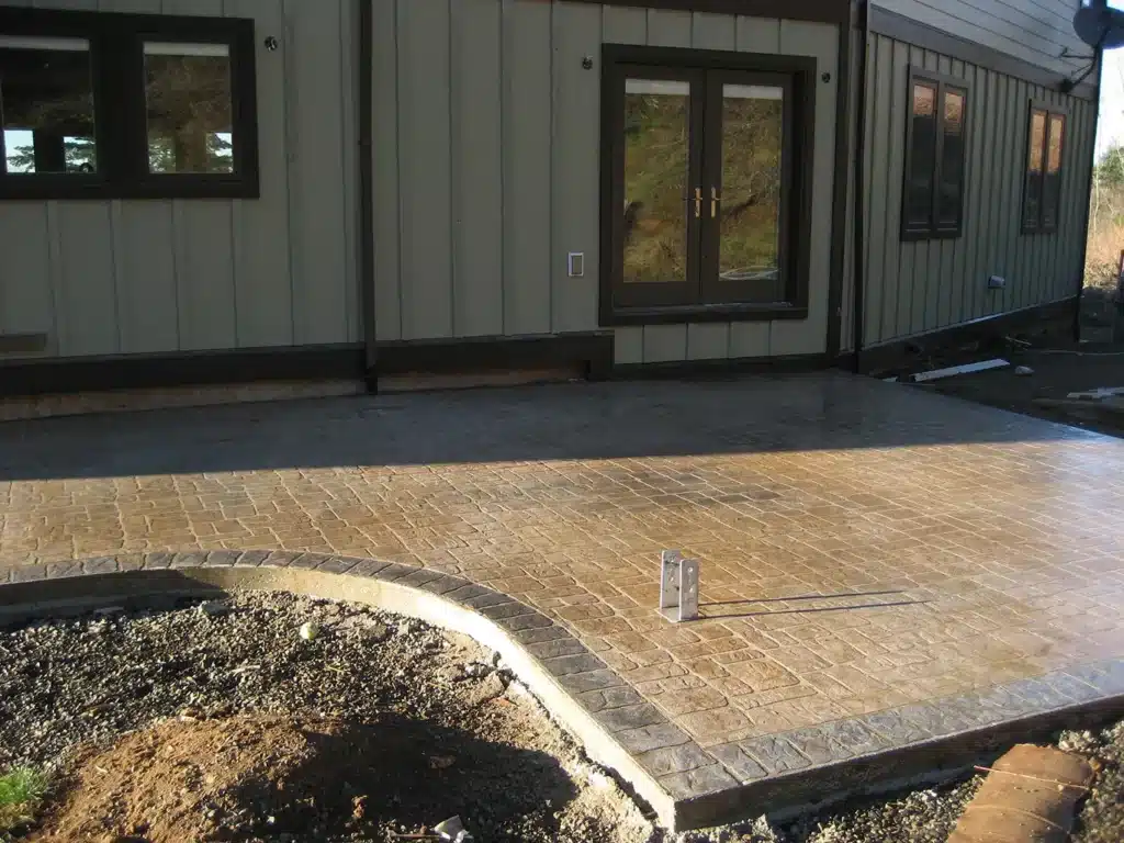 Newly installed stamped concrete patio beside home exterior