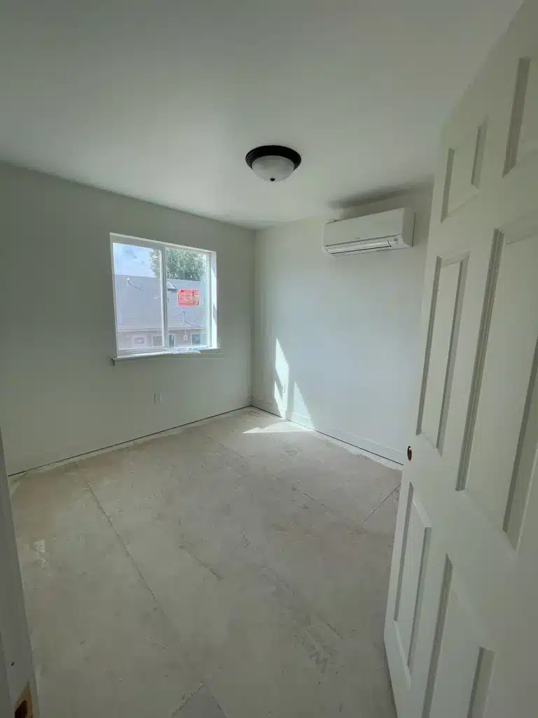 Bedroom under construction with window light and mini-split unit