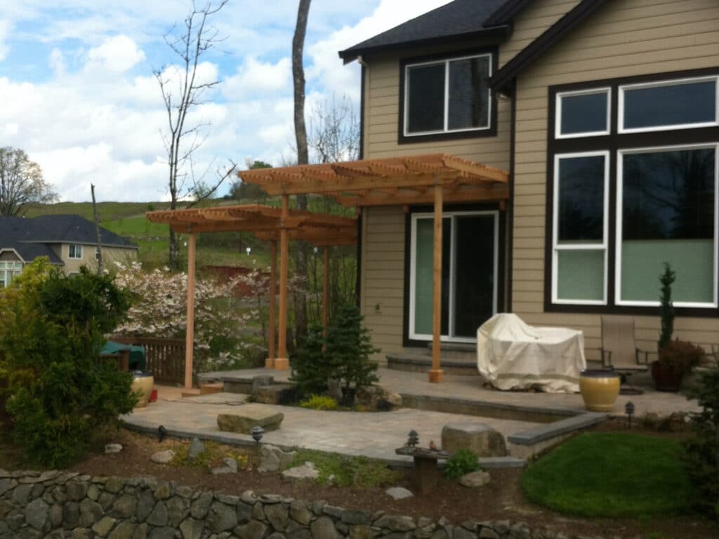 Cedar pergola covering a stone patio area behind a home in Wilsonville, Oregon