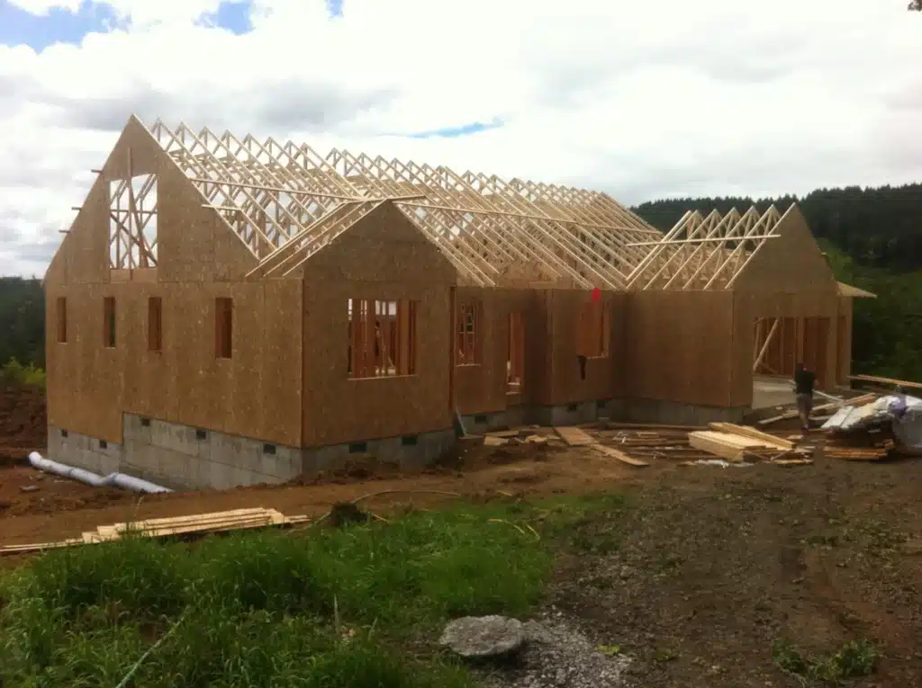 Framed custom home with roof trusses set and structural shell taking shape in Hillsboro, Orego
