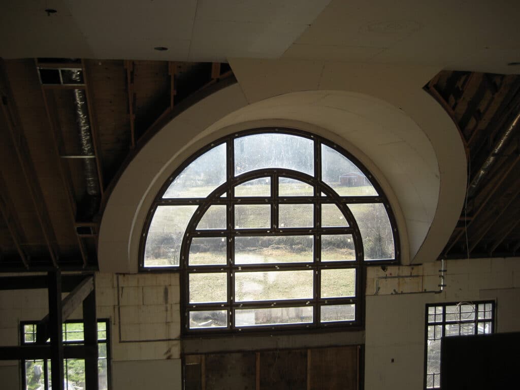 Close-up of custom arched window framing during installation in Sherwood home
